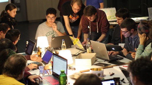 Menschen sitzen mit Notebooks an einem Gruppentisch im Foyer des Audimax.